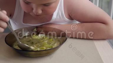 有食欲的胖小子在厨房里吃汤，概念肥胖的孩子。